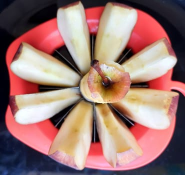Apple shown beautifully in apple cutter like flower shape and it tempts to eat in black background