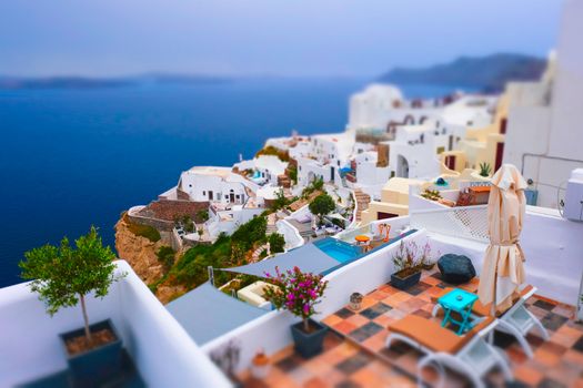 Famous greek iconic selfie spot tourist destination Oia village with traditional white houses and windmills in Santorini island, Greece. Toy camera tilt shift miniature effect