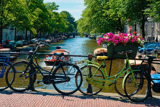 Typical Amsterdam view - Amsterdam canal with boats and bicycles on a bridge with flowers. Amsterdam, Netherlands