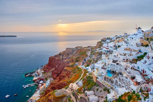 Famous greek iconic selfie spot tourist destination Oia village with traditional white houses and windmills in Santorini island on sunset in twilight, Greece