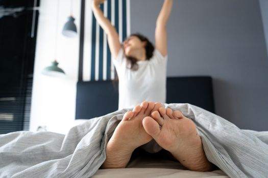 Beautiful girl wakes up in a good mood in a stylish apartment. View from the feet.