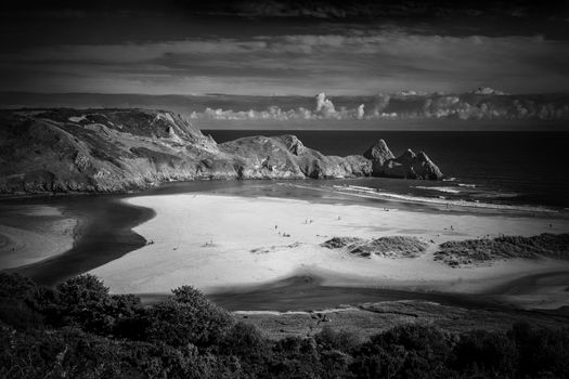 Three Cliffs Bay on the Gower Peninsular West Glamorgan Wales UK which is a popular Welsh coastline attraction of outstanding beauty monochrome image