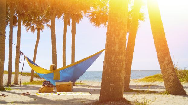 Romantic couple relaxing on tropical hammock. Young couple in love relaxing in a hammock by the beach. Summer luxury vacation. Lens Optical Flare. Vintage Overlay Effect.