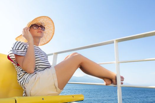 Beautiful, romantic blonde woman relaxeing on summer vacations traveling by cruse ship ferry boat. Summer vacation lifestyle.