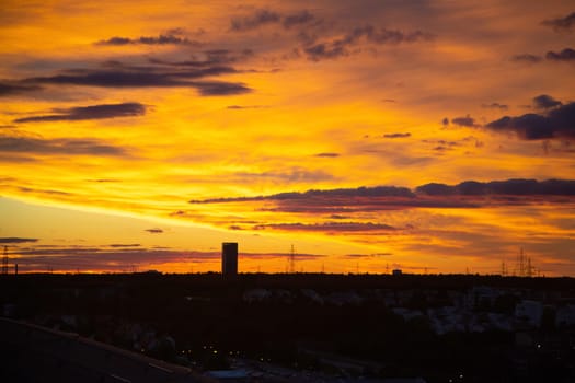 City in sunset light, silhouette of the buildings over colorful sky background, beautiful evening cityscape. Bright sunset over the European city. Panorama of the night city.