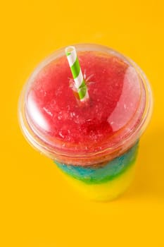 Colorful slushie of differents flavors with straw on yellow background