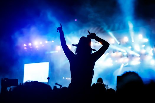 Silhouette of a girl with raised hands at a mass event. Party in a nightclub.