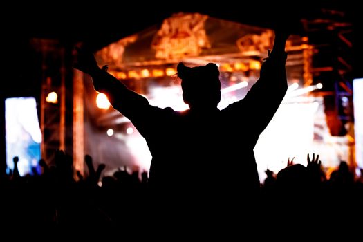 Silhouette of girl with raised hands on music concert.