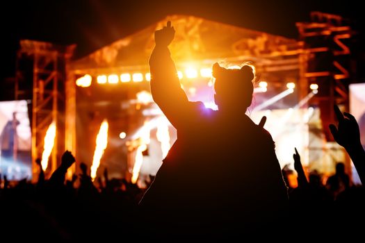 Silhouette of girl with raised hands on music concert.