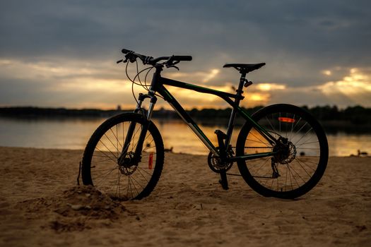 Silhouette of sports bicycle on a beach. Sunset