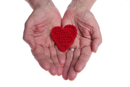 Old woman's hands giving woollen heart 