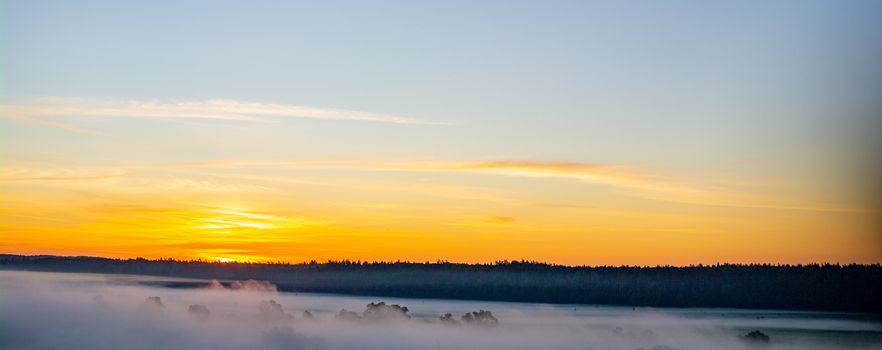 Predawn morning fog and orange-blue sky with clouds.