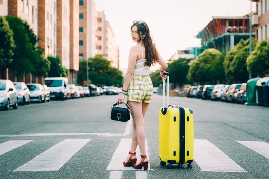 woman with a yellow suitcase and a bag on the street.