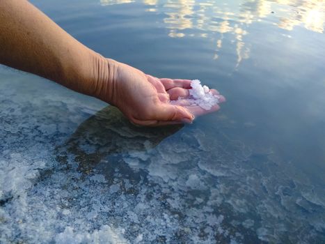 A piece of salt on the woman hand. Salt Lake. Natural salt. Ukrainian lake for salt production