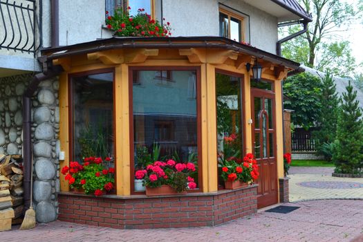 Flower shop with red flowers at city street park. Florist shop. Wooden facade of shop