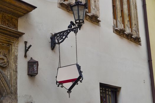 Forged decorative black sign with place for text and logo hanging on the wall. Old town cafe.