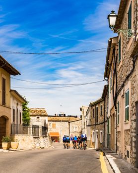 Cycling athletes on road in mediterranean village on Mallorca island, Spain