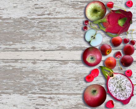 Fresh fruits on light wooden background. Dragon fruit, apple, peach, raspberry and cherry. Top view with copy space