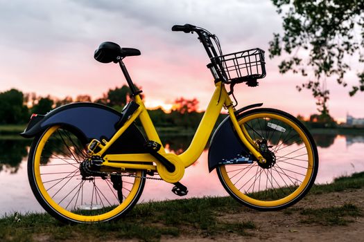 Yellow bike on the lake. Sunset pink sky