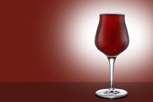 Red ale beer in tulip wineglass isolated on ruby background.