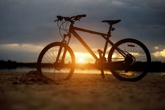 Silhouette of sports bicycle on a beach. Sunset