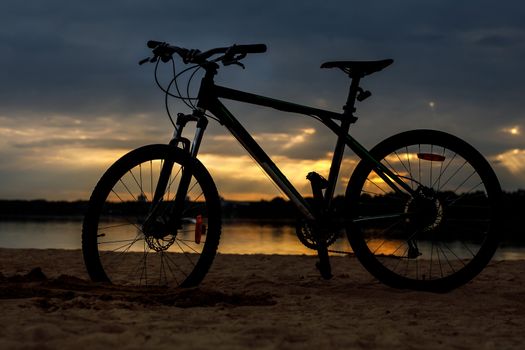 Silhouette of sports bicycle on a beach. Sunset