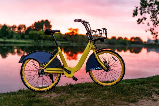 Yellow bike on the lake. Sunset pink sky