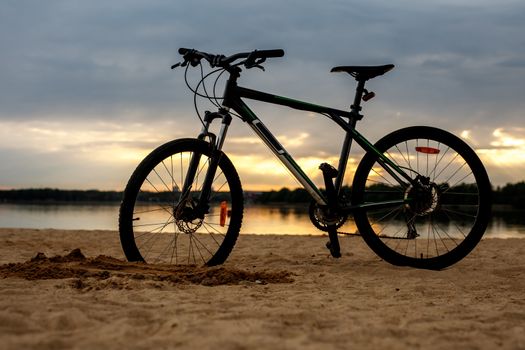 Silhouette of sports bicycle on a beach. Sunset