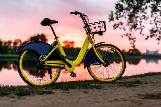 Yellow bike on the lake. Sunset pink sky