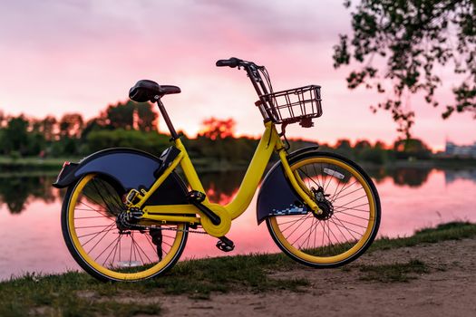 Yellow bike on the lake. Sunset pink sky