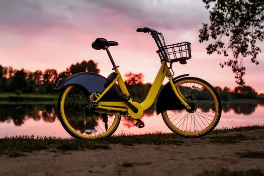 Yellow bike on the lake. Sunset pink sky