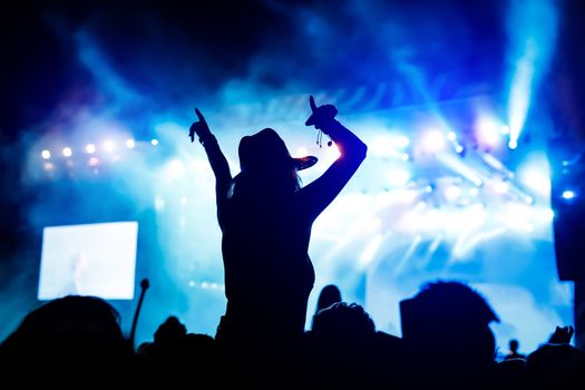 Silhouette of girl with raised hands on music concert.