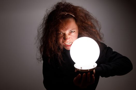 Fortuneteller holding a glowing ball in her hands.