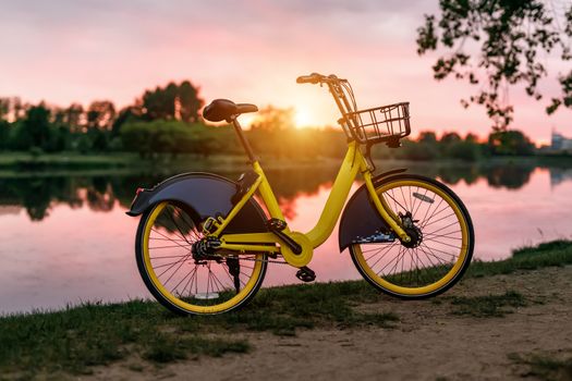 Yellow bike on the lake. Sunset pink sky