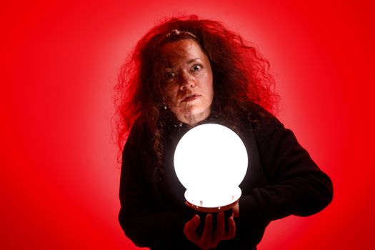 Fortuneteller holding a glowing ball in her hands. Red background