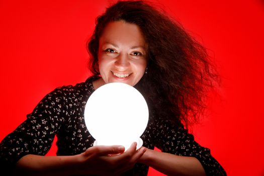 Smiling woman with a luminous ball. Red background