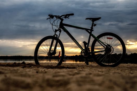 Silhouette of sports bicycle on a beach. Sunset