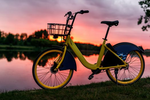 Yellow bike on the lake. Sunset pink sky