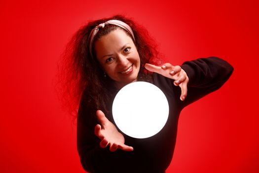 Smiling girl holding a glowing ball in her hands Red background