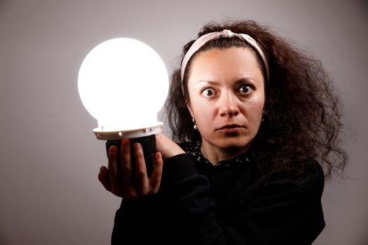 Fortuneteller holding her hands a glowing ball. Surprise on the face