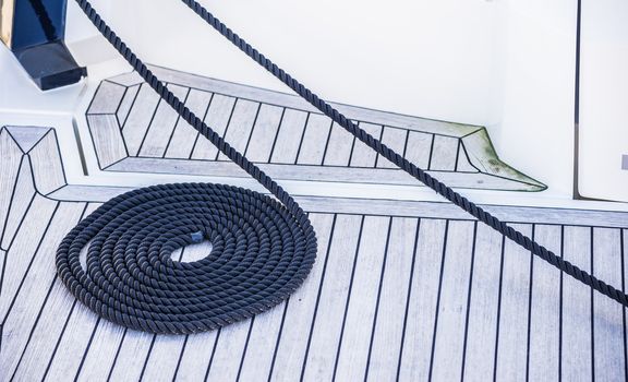 View of swirled curled nautical rope bow on boat deck, mooring line