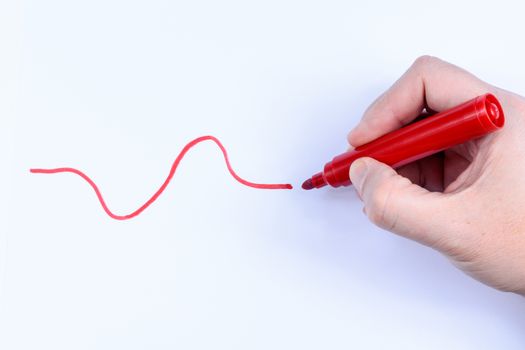 Hand holding a red  pen drawing a wavey line isolated on white background