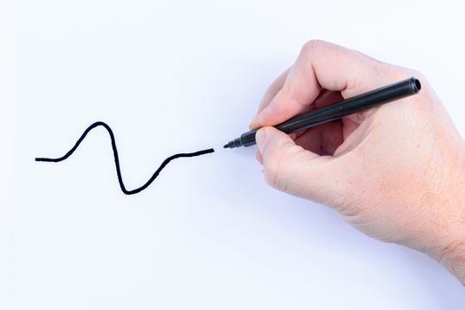 Hand holding a black  pen drawing a wavey line isolated on white background