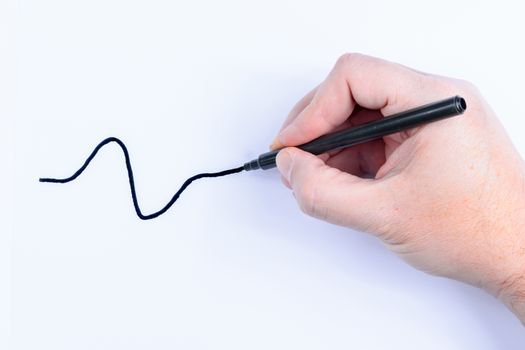 Hand holding a black  pen drawing a wavey line isolated on white background