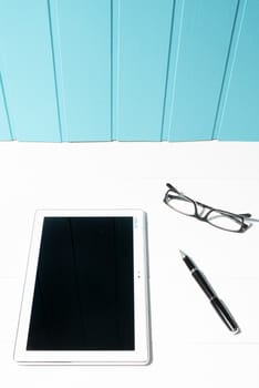 a tablet and a pair of glasses on a white wooden table