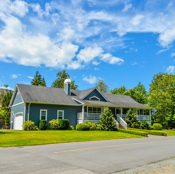 Big residential house on a country side with asphalt road in front. Big family home in British Columbia, Canada