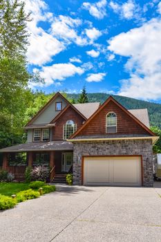 Residential house with wide concrete driveway, double garage door, and decorated front yard. Single family house on blue sky background