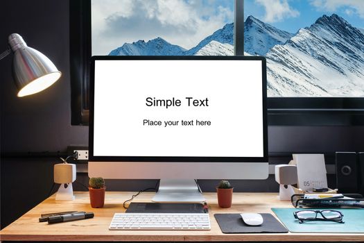 Graphic designer's workspace equipped with a pen tablet, a computer and white screen for text with beautiful snow moutain from the window 