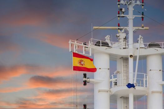 The flag of Spain flying on the tower of a white cruise ship