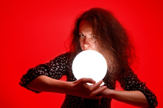 Woman with a luminous ball. Red background